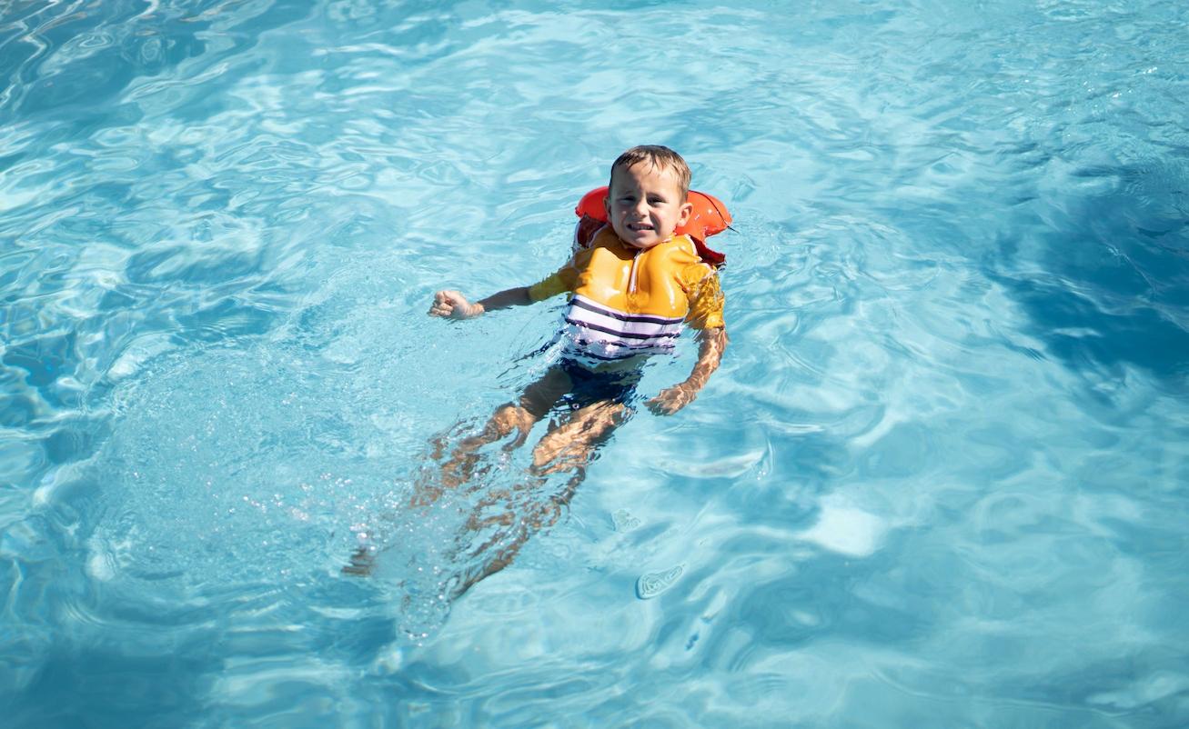 Ragazzo in piscina con maglietta gonfiabile anti annegamento per bambini