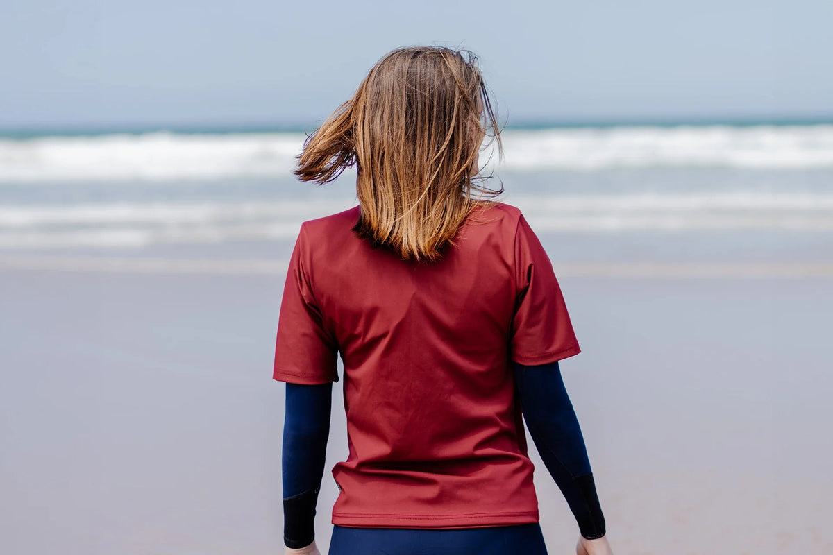 Femme sur une plage et portant le tee-shirt anti-noyade adulte automatique Floatee, manches courtes, rouge, vue de dos