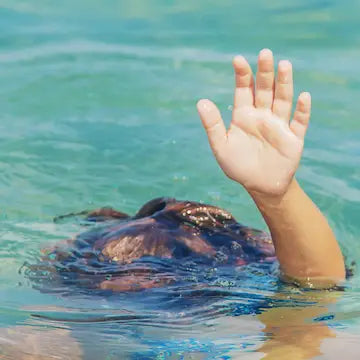 Un bambino che affonda, di cui si vede solo la cima della testa e la mano