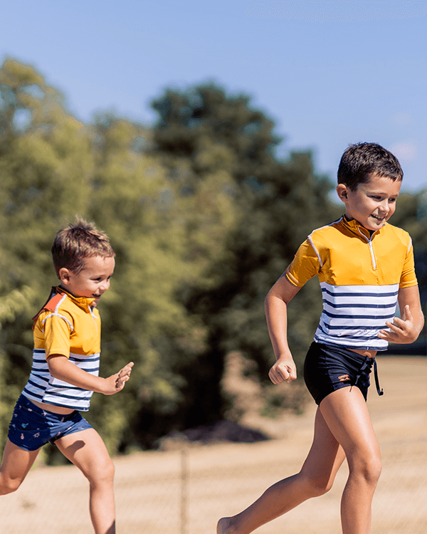 La maglietta gialla anti annegamento per bambini su due bambini che corrono