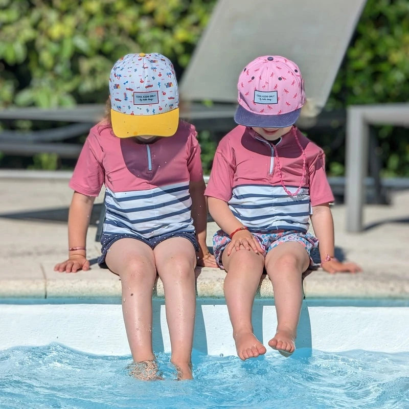 Due ragazze in piedi vicino a una piscina con i piedi nell'acqua che indossano magliette rosa contro l'annegamento dei bambini