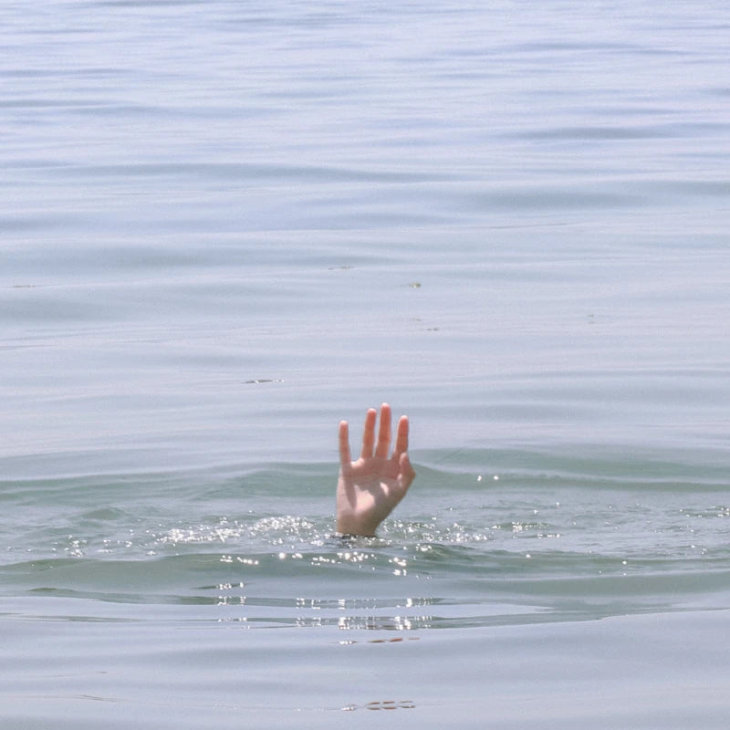 Una foto di una persona che affonda. Si vede solo la sua mano che sporge.